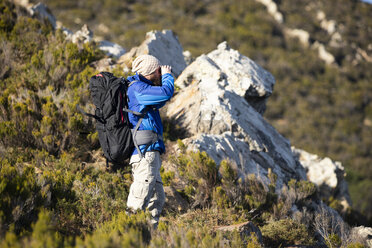 Spanien, Andalusien, Tarifa, Mann beim Wandern in den Bergen mit Blick durch ein Fernglas - KBF00412