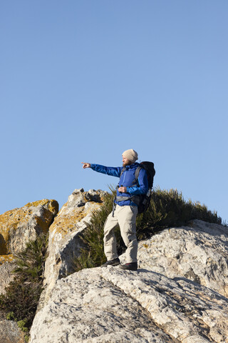 Spain, Andalusia, Tarifa, man on a hiking trip standing on rock pointing his finger stock photo