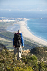 Spanien, Andalusien, Tarifa, Mann auf Wanderschaft an der Küste mit Blick auf die Aussicht - KBF00424