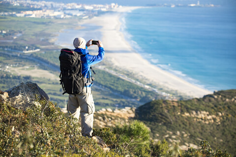 Spain, Andalusia, Tarifa, man on a hiking trip at the coast taking a cell phone picture stock photo