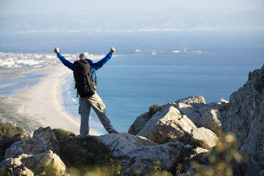 Spanien, Andalusien, Tarifa, Mann auf einem Wanderausflug an der Küste mit Blick auf Aussicht jubelnd - KBF00426