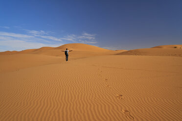 Morocco, back view of man with backpack standing on desert dune - EPF00544