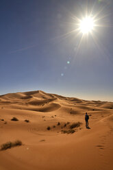 Marokko, Sahara, Mann mit Rucksack steht auf einer Wüstendüne und schaut auf die Aussicht - EPF00550