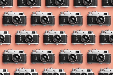 Photo cameras organized in a row over coral color background - DRBF00128