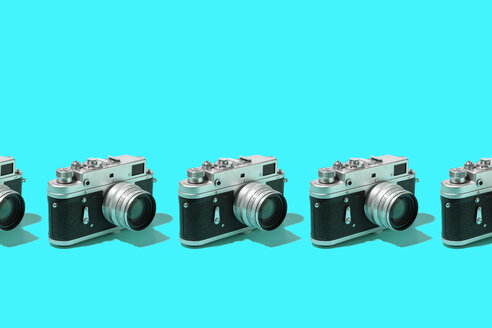 Fotokameras in einer Reihe über blauem Hintergrund organisiert - DRBF00132