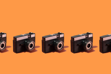 Kunststoff-Fotokameras in einer Reihe über orangefarbenen Hintergrund organisiert - DRBF00133