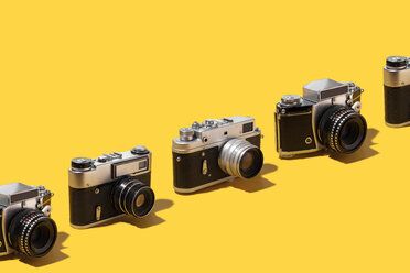 Photo cameras organized in a row over yellow background - DRBF00135