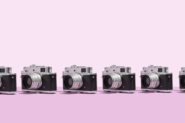 Photo cameras organized in a row over pink background - DRBF00136