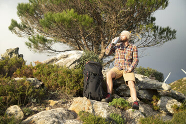 Spanien, Andalusien, Tarifa, Mann auf einer Wandertour macht eine Pause und trinkt aus einem Flachmann - KBF00444