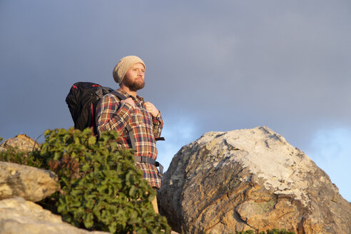 Spanien, Andalusien, Tarifa, Mann auf Wanderschaft an einem Felsen mit Blick auf die Aussicht - KBF00451