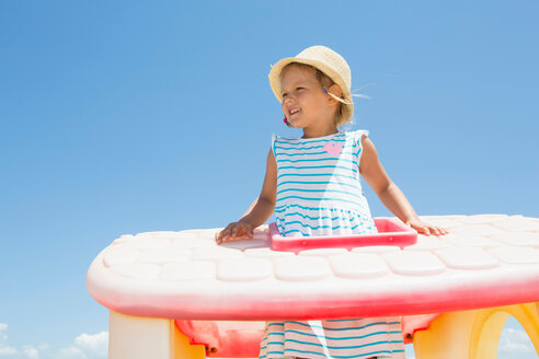 Mädchen mit Sonnenhut schaut von einem Plastikdach am Strand, Castellammare del Golfo, Sizilien, Italien - CUF47895