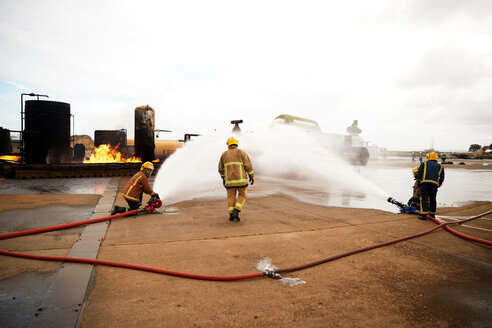 Feuerwehrleute beim Training, Spritzen von Wasser auf das Feuer in der Übungsanlage - CUF47979