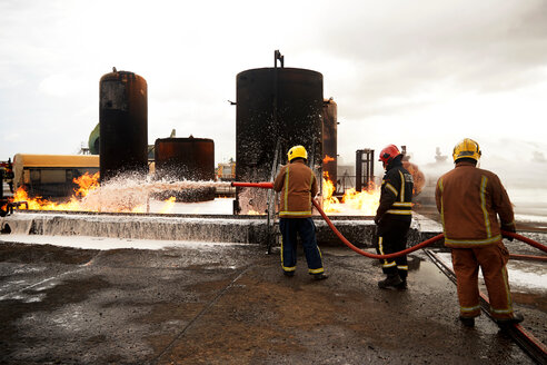 Feuerwehrleute beim Training, Sprühen von Löschschaum auf den Brand eines Öllagertanks in einer Übungsanlage - CUF47981
