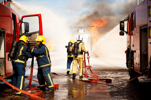 Ausbildung von Feuerwehrleuten, Team von Feuerwehrleuten beim Löschen eines simulierten Hubschrauberbrandes in einer Ausbildungseinrichtung - CUF47982