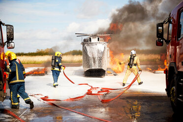 Ausbildung von Feuerwehrleuten, Team von Feuerwehrleuten beim Löschen eines simulierten Hubschrauberbrandes in einer Ausbildungseinrichtung - CUF47983