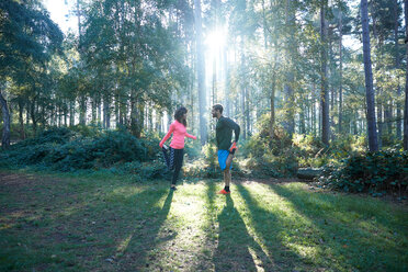 Läufer und Läuferinnen dehnen die Beine und wärmen sich im sonnigen Wald auf - CUF47987