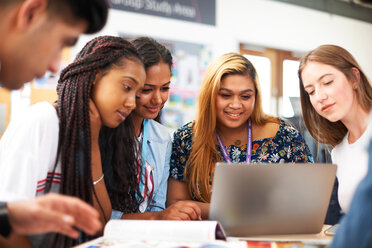 Weibliche und männliche Hochschulstudenten mit Blick auf den Laptop im Klassenzimmer - CUF48002