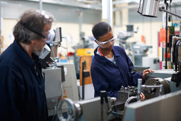 Lecturer teaching student to operate machine in workshop - CUF48019