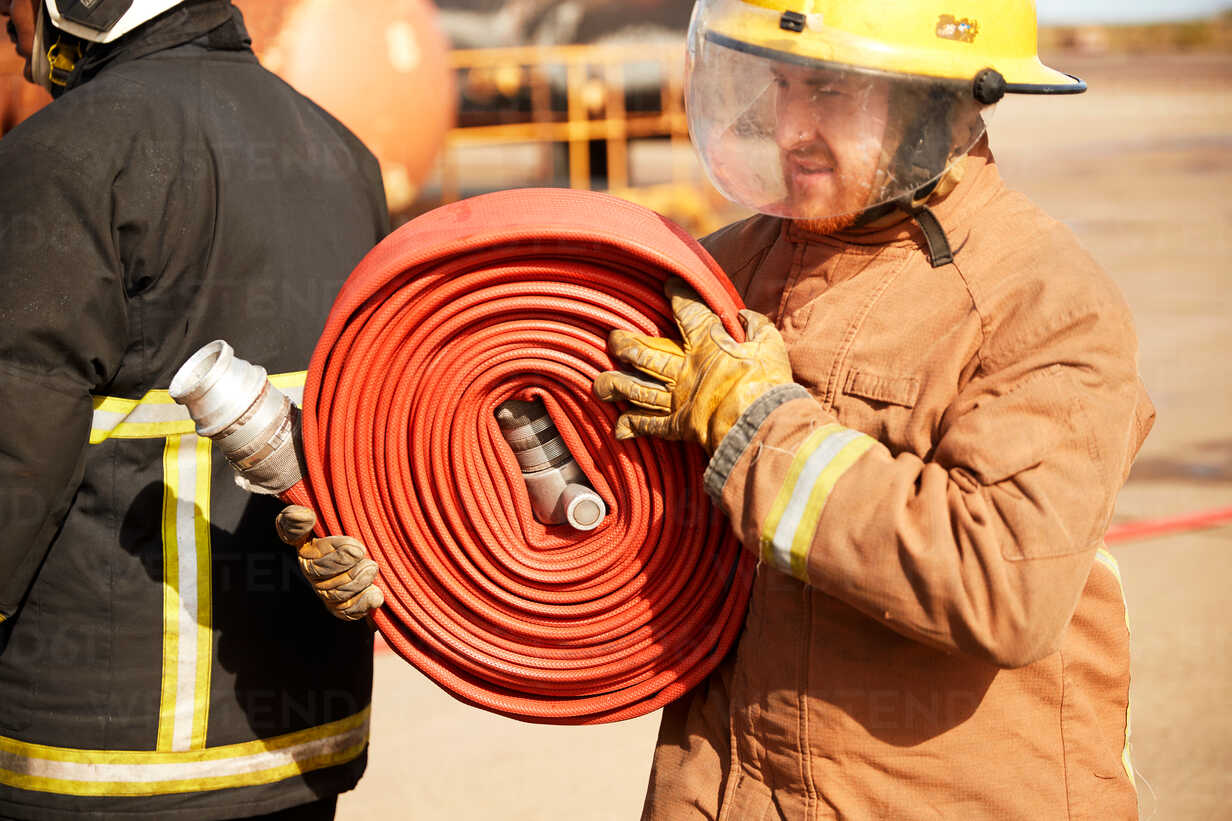 Fireman carrying fire hose reel, Darlington, UK stock photo