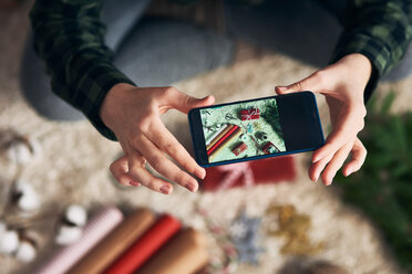 Woman taking photo of Christmas gifts and giftwrap - CUF48151