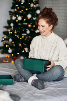 Frau packt Weihnachtsgeschenke auf dem Bett ein - CUF48164