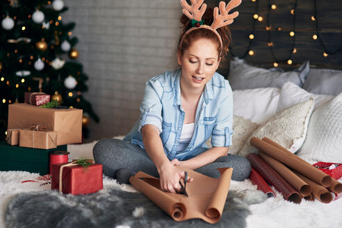 Frau packt Weihnachtsgeschenke auf dem Bett ein - CUF48165