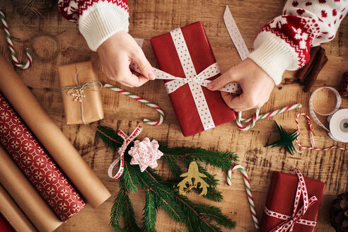 Frau bindet Schleife an Weihnachtsgeschenk - CUF48171