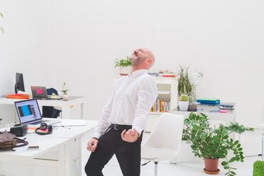 Crazy businessman playing air guitar in office - CUF48228