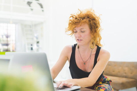 Geschäftsfrau tippt auf einem Laptop am Bürotisch, lizenzfreies Stockfoto