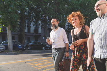 Mittlere erwachsene Frau und männliche Freunde unterhalten sich beim Spazierengehen auf dem Bürgersteig der Stadt - CUF48235