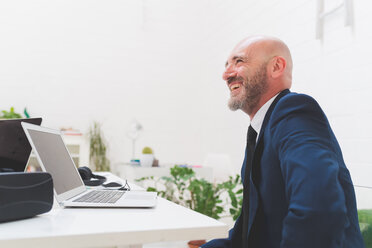 Businessman laughing at office desk - CUF48262