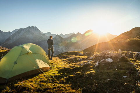 Hiker by tent enjoying view, Karwendel region, Hinterriss, Tirol, Austria stock photo