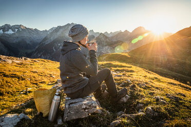 Hiker taking break with warm drink, Karwendel region, Hinterriss, Tirol, Austria - CUF48306