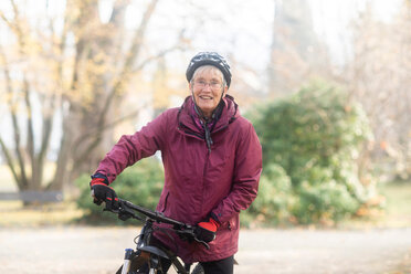Ältere Frau auf dem Fahrrad im Park - CUF48360