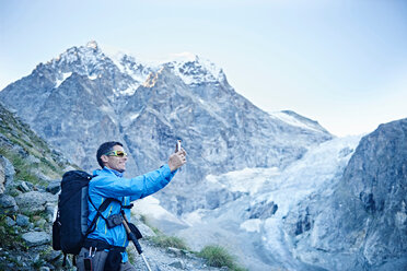 Hiker taking photograph, Mont Cervin, Matterhorn, Valais, Switzerland - CUF48388