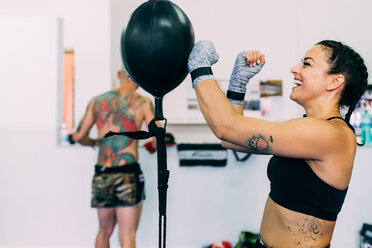 Woman using punch bag in gym - CUF48399