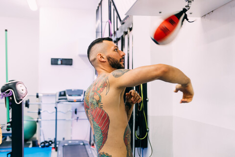 Mann benutzt Sandsack im Fitnessstudio, lizenzfreies Stockfoto