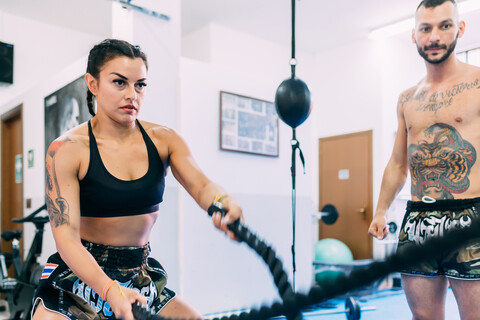 Frau benutzt Seilpeitschen beim Training im Fitnessstudio, lizenzfreies Stockfoto