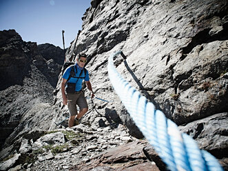 Wanderer, der ein Seil benutzt, um eine Felswand zu besteigen, Mont Cervin, Matterhorn, Wallis, Schweiz - CUF48428