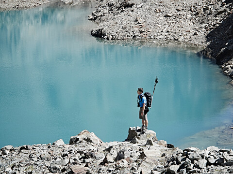 Hiker on rock by edge of lake, Mont Cervin, Matterhorn, Valais, Switzerland stock photo