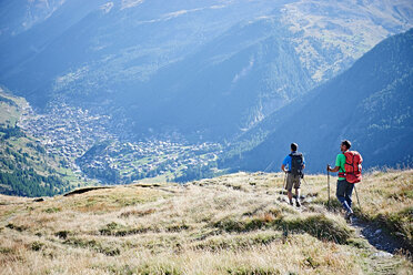 Hikers on grassy cliff overlooking valley, Mont Cervin, Matterhorn, Valais, Switzerland - CUF48433