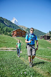 Wanderer auf üppiger grüner Wiese, Chalets im Hintergrund, Mont Cervin, Matterhorn, Wallis, Schweiz - CUF48434