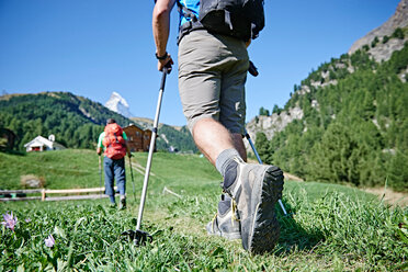 Wanderer auf üppiger grüner Wiese, Chalets im Hintergrund, Mont Cervin, Matterhorn, Wallis, Schweiz - CUF48435