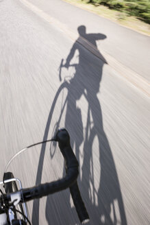 Mann auf Fahrrad wirft Schatten auf Straße in Schweden - FOLF10262