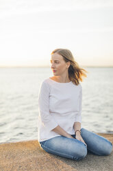 Junge Frau sitzt am Meer in Karlskrona, Schweden - FOLF10284