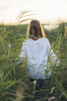 Junge Frau, die durch ein Grasfeld in Karlskrona, Schweden, läuft - FOLF10287