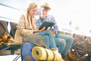 Junges Paar am Flughafen, sitzend, umgeben von Rucksäcken, mit digitalem Tablet, Tiefblick - ISF20122