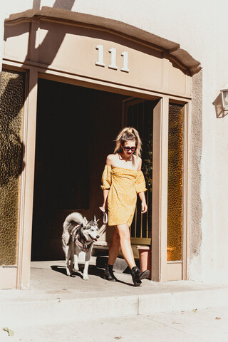 Junge Frau mit Hund am Eingang eines Gebäudes, lizenzfreies Stockfoto