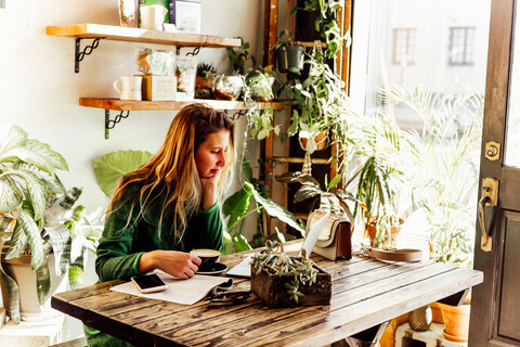 Junge Frau benutzt Laptop in einem Cafe, lizenzfreies Stockfoto