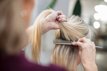 Friseurin stylt das Haar eines Kunden im Salon - ISF20147